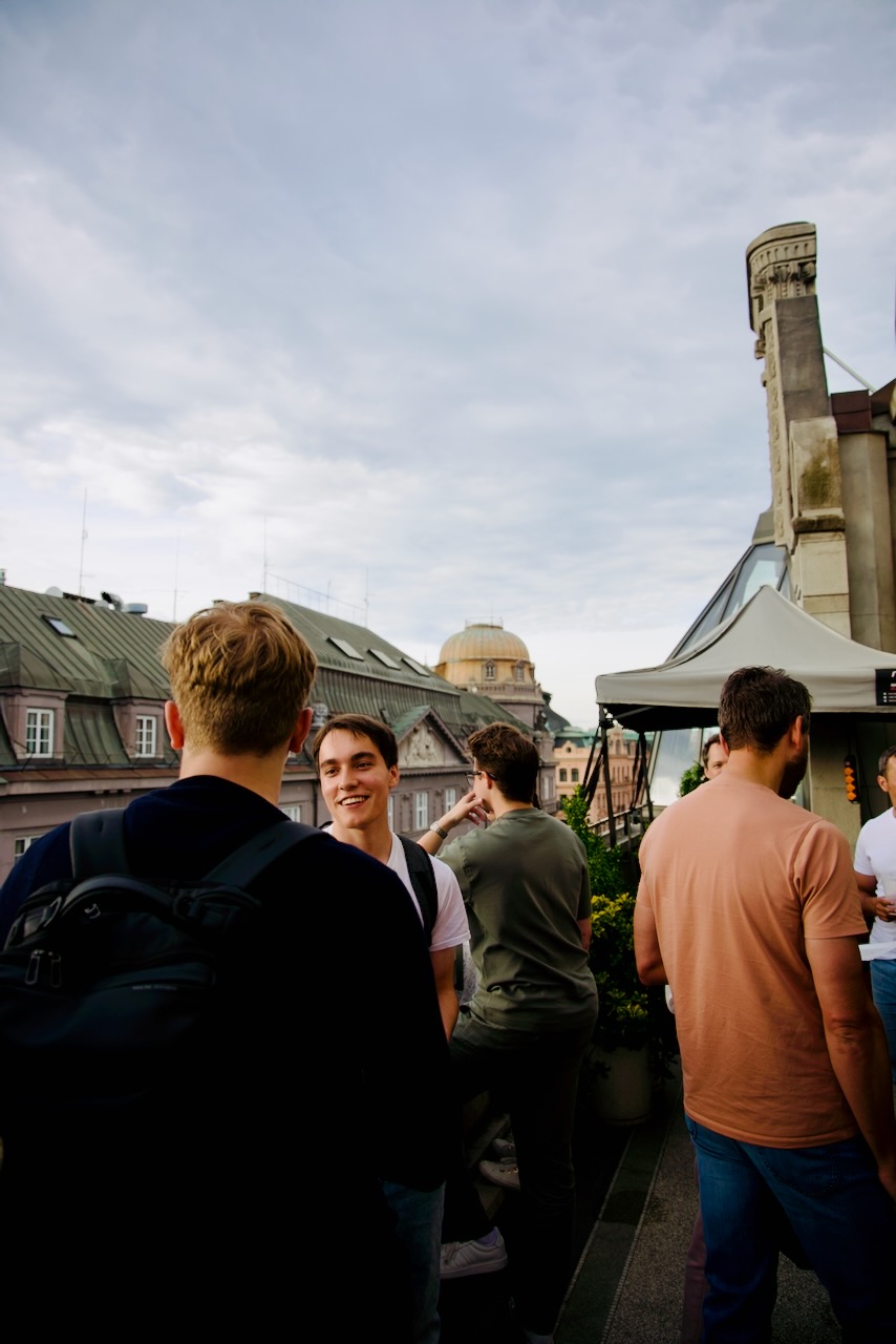 Andrew Zbytek with attendees on the rooftop, Prague skyline behind
