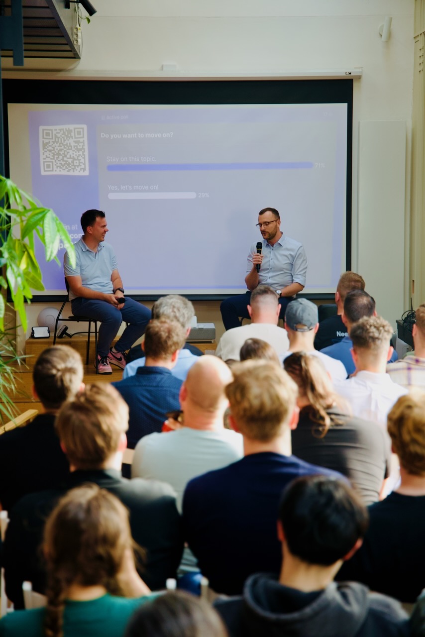 Andrew Zbytek and Jirka Helmich mid-fireside, with the live move-on poll visible on the screen behind them